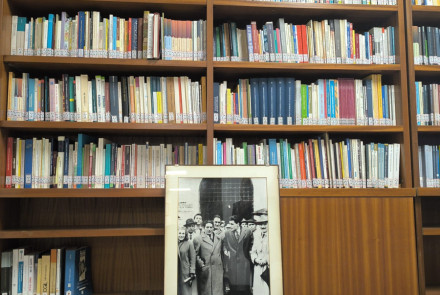 l'immagine mostra una libreria con molti libri, e in basso appoggiata una cornice rettangolare con all'interno una fotografia che mostra alcuni uomini, tra cui Giuseppe Di Vittorio